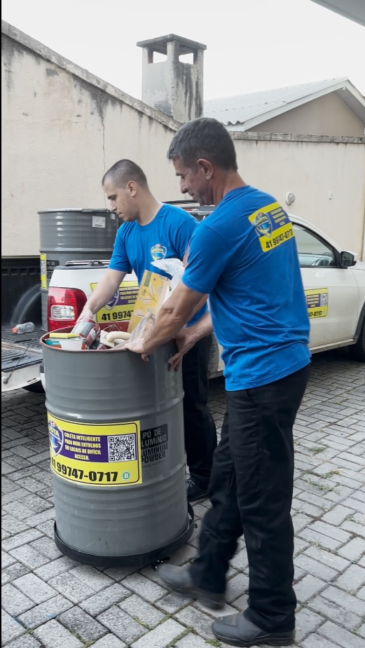 Equipe movimentando tambor metálico de 200 litros